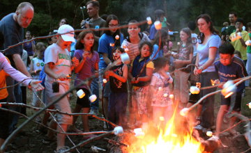 Photo of Campers gathered around a bonfire.